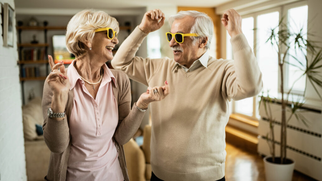 Playful Senior Couple Having Fun While Dancing At Home.