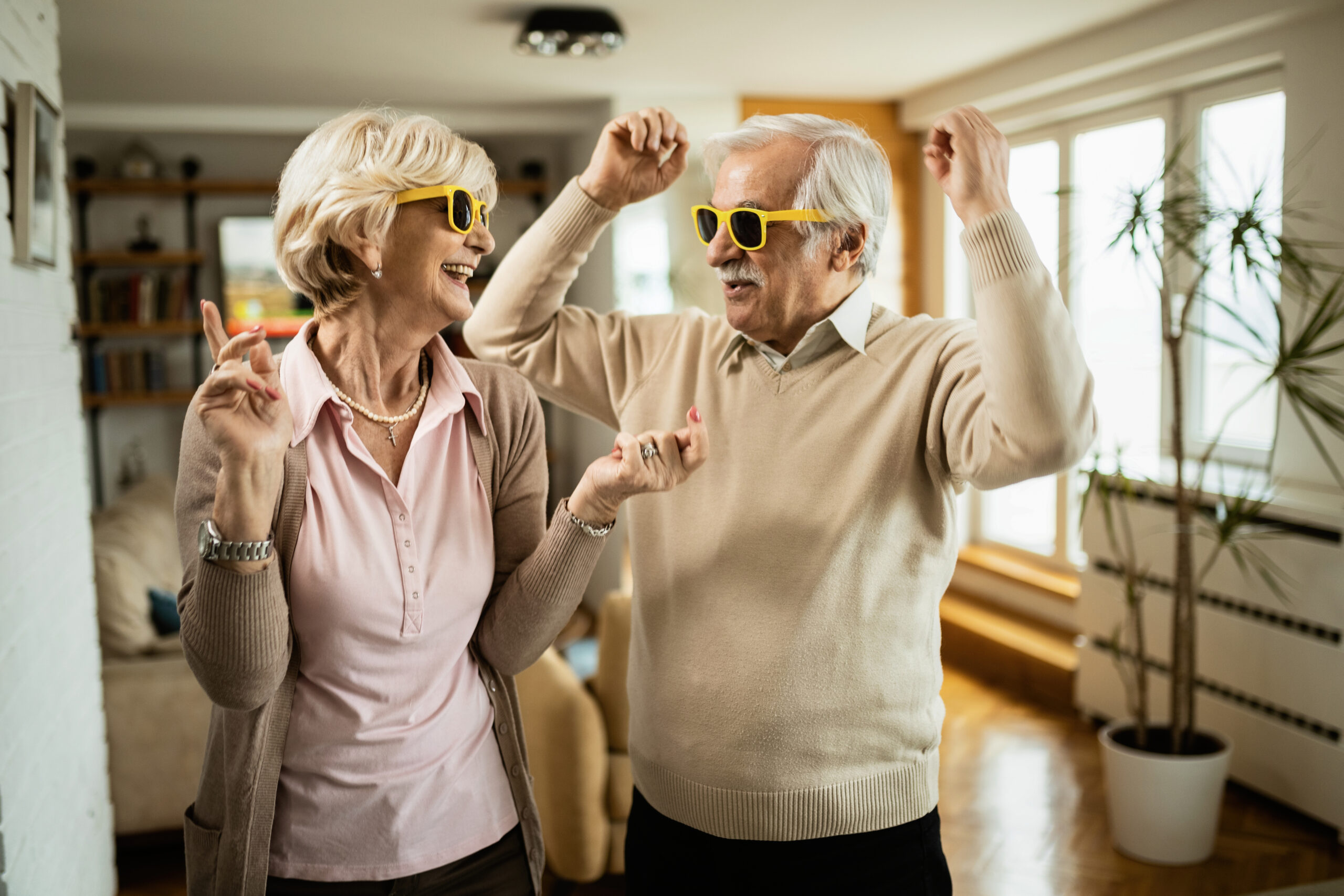 Playful Senior Couple Having Fun While Dancing At Home.